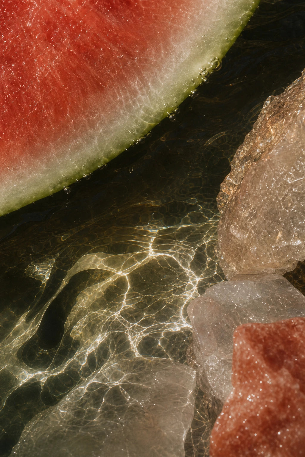 Watermelon, water and clear ice lit by warm sunlight